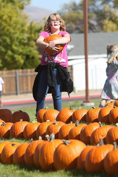 Eight-year-old Grace Billow, a third-grader at Seeliger, carries a pumpkin on Saturday during the school&#039;s annual pumpkin patch.