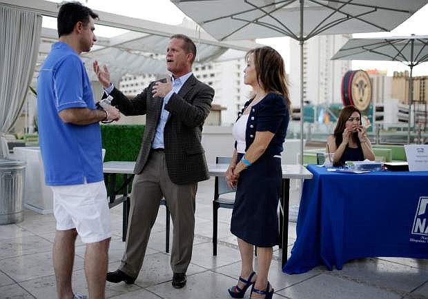 In this photo taken on July 23, 2014, GOP lieutenant governor candidate Mark Hutchison, second from left, speaks with Tony Medina, left, and Olga Naccari-Torres at an event in Las Vegas. Nevada governor Brian Sandoval, and Senate Majority Leader Reid are deeply involved in the campaign in Nevada for lieutenant governor, since the winner would replace Sandoval should the highly popular governor decide to run against Reid. (AP Photo/John Locher)