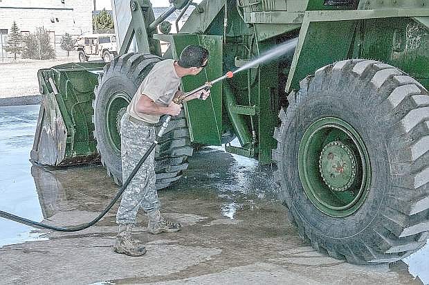 Staff Sgt. Brent Peden, a surface maintenance mechanic at the Combined Support Maintenance Shop in Carson City uses the new Net Zero Heavy Solids Wash Rack cannon to remove debris from a front loader before conducting a maintenance check.