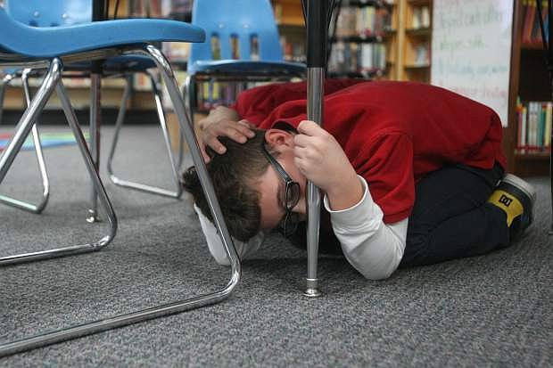 Hayden Breiter covers his head under a table at the Seeliger Elementary School library on Thursday during the earthquake drill.