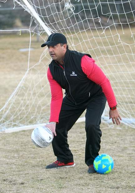 Soccer coach Ian Hill feeds balls to players during a kicking drill on Monday.