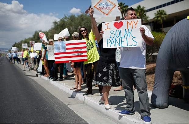 Protestors, including Ronald Brittan, right, line up along the street during a rally in front of NV Energy Wednesday, April 22, 2015, in Las Vegas. Hundreds of activists gathered outside NV Energy headquarters in Las Vegas to protest a state cap affecting rooftop solar installations and urge the Legislature to lift it. (AP Photo/John Locher)