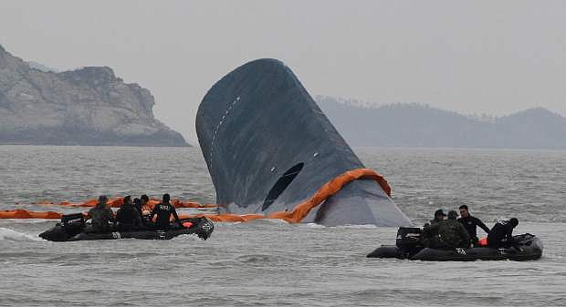 AP10ThingsToSee - South Korean Coast Guard officers search for missing passengers aboard a sunken ferry in the waters off the southern coast near Jindo, South Korea on Thursday, April 17, 2014. An immediate evacuation order was not issued for the ferry, likely with scores of people trapped inside, because officers on the bridge were trying to stabilize the vessel after it started to list amid confusion and chaos, a crew member said Thursday. (AP Photo/Ahn Young-joon)