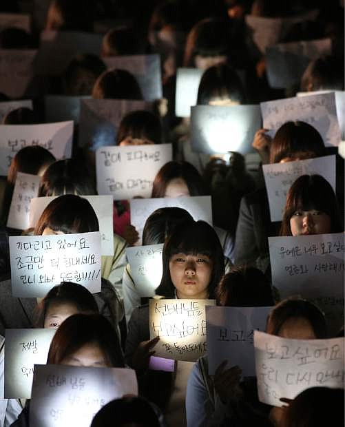 Students hold papers with candles for safe return of their friends aboard the sunken ferry Sewol at Danwon High School in Ansan, south of Seoul, South Korea, Friday, April 18, 2014. Rescuers scrambled to find hundreds of ferry passengers still missing Friday and feared dead in the waters off the country&#039;s southern coast, as fresh questions emerged about whether quicker action by the captain of the doomed ship could have saved lives. (AP Photo/Yonhap) KOREA OUT