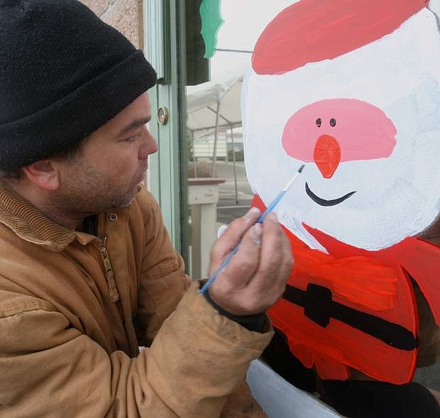 Artist Glen Coates paints a smile on Santa while decorating the front door and windows of the Twisted Spoke Bar &amp; Grill on Tuesday.
