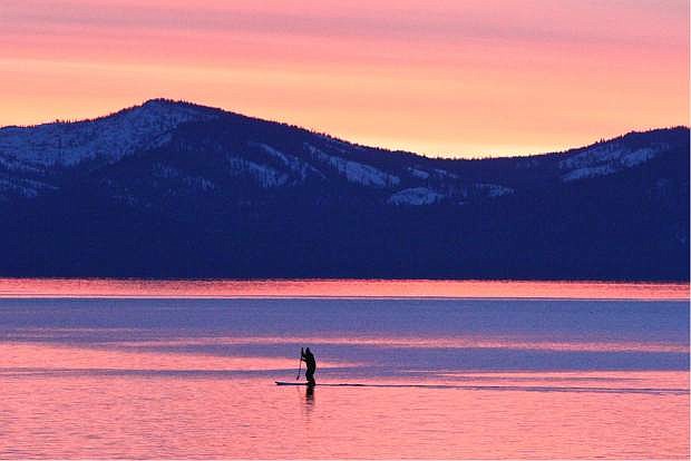 A standup paddleboarder glides across a smooth Lake Tahoe Saturday at sunset near Kennedy Point.