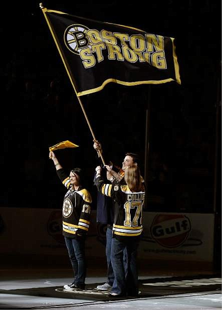 Rob Rogers, Jenn Rogers, and Jennifer Lemmerman, wave a Boston Strong banner before Game 3 of the NHL hockey Stanley Cup Finals between the Boston Bruins and the Chicago Blackhawks in Boston, Monday, June 17, 2013. The three are relatives of MIT police officer Sean Collier, killed during confrontation with suspects in the Boston Marathon bombing on April 15. (AP Photo/Elise Amendola)