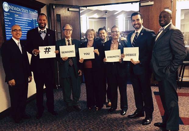 This photo taken Feb. 5, 2015 and provided by Peter Koltak shows, from left, Nevada Democratic Senators Mo Denis, Aaron Ford, David Parks, Joyce Woodhouse, Mark Manendo, Pat Spearman, Ruben Kihuen and Kelvin Atkinson posing for for a photo in Carson, Nev. The message is part of an informal social media campaign meant to encourage Sen. Debbie Smith, who was scheduled to receive surgery on a brain tumor on Feb. 6. (AP Photo/Peter Koltak)