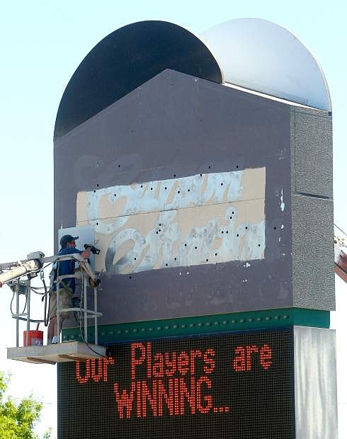 Workers paint over the former Carson Station logo on Tuesday to create new signage for the Max Casino.