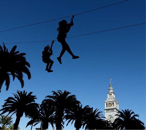 People dangle from a zip line at Super Bowl City Tuesday, Feb. 2, 2016 in San Francisco. The Denver Broncos play the Carolina Panthers in the NFL Super Bowl 50 football game Sunday, Feb. 7, 2015, in Santa Clara, Calif. (AP Photo/Charlie Riedel)