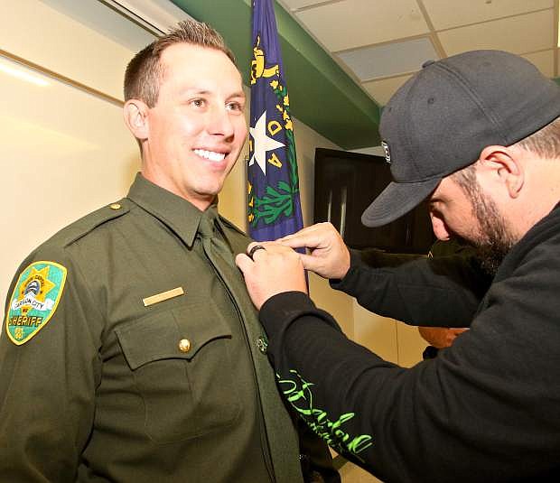 Deputy Daniel Henneberger has his badge pinned on by longtime friend Bryan Williams Friday afternoon at the Carson City Sheriff&#039;s Office.