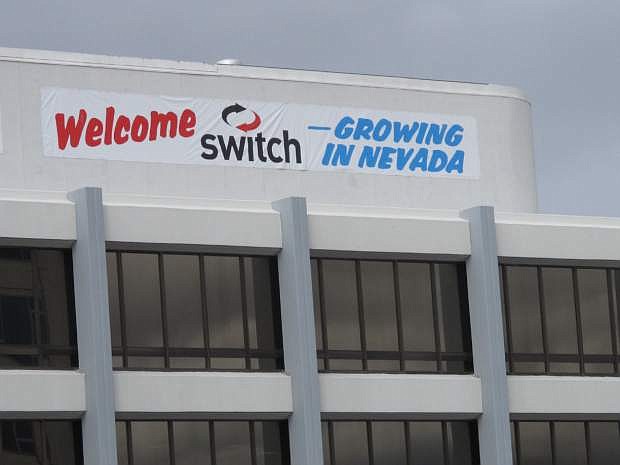 The managers of the US Bank Building who erected a banner to welcome Tesla Motors to northern Nevada added a sign on Friday, Jan. 16, 2015, for the Las Vegas-based Switch after the company announced plans to build the biggest data storage center in the world east of Reno. The $1 billion facility is planned at the same industrial park where Tesla is building the biggest lithium battery factory in the world to power its electric cars. (AP Photo/Scott Sonner)