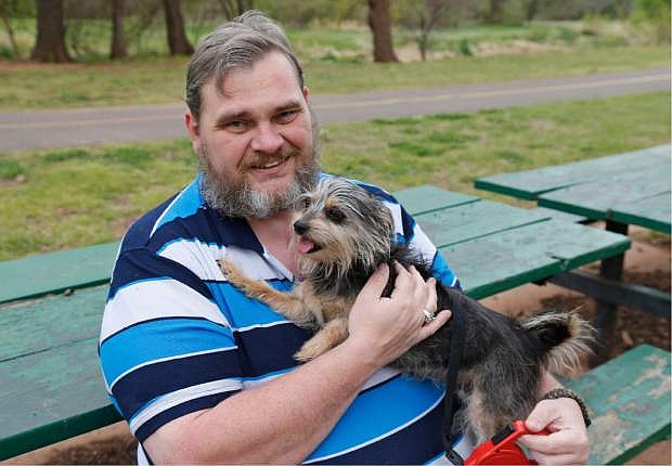 Jerry Starr is pictured with Tobi, his four-year-old shih tzu-yorkie mix dog at a park in Del City, Okla., Thursday, April 17, 2014. Starr was not allowed to take the dog into a shelter during the May 20, 2013 tornado and opted to stay outside the shelter in his car with his dog. (AP Photo/Sue Ogrocki)