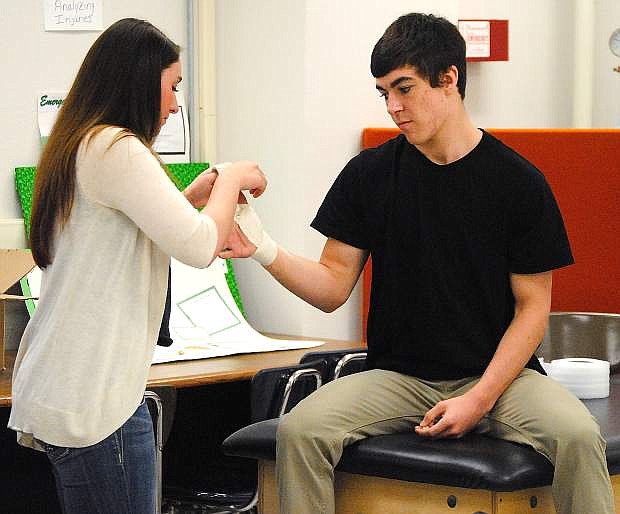 Churchill County High School senior Shelby Lawry wraps fellow senior Clay Amezquita&#039;s hand during their Sports Medicine I class. Lawry will be a student trainer at the University of Nevada, Reno in the fall.