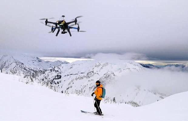 This Dec. 2014 photo shows a drone hovering by a skier as he makes his way down mountainside at resort at Revelstoke, B.C., Canada. Some US ski resorts are exploring the possibility of &quot;drone zones&quot; where professionally operated drones can produce customized video that show off individuals skiers in action. (Jason Soll/Cape Productions via AP)