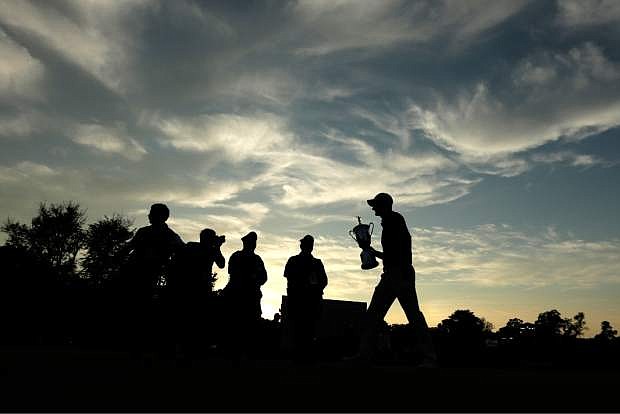 Justin Rose, of England, walks on the 18th green with the trophy after winning the U.S. Open golf tournament at Merion Golf Club, Sunday, June 16, 2013, in Ardmore, Pa. (AP Photo/Charlie Riedel)