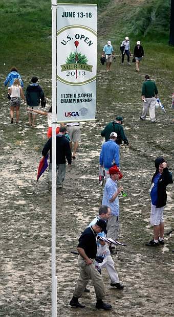 Spectators make their way down a muddy path during practice for the U.S. Open golf tournament at Merion Golf Club, Monday, June 10, 2013, in Ardmore, Pa. (AP Photo/Gene J. Puskar)