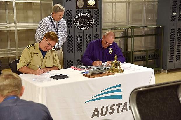 USNS Carson City Captain Robert Wiley, left, Austal EPF Contracts Manager Tommy Jordan, standing, and SUPSHIP GC Rep John Hessin are seen on Friday.
