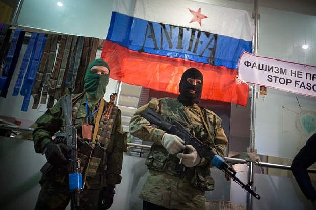 Masked pro-Russian gunmen guard an entrance of the Ukrainian regional office of the Security Service with a Russian National flag is in background in Luhansk, Ukraine, Monday, April 21, 2014.  U.S.Vice President Joe Biden is heading to Ukraine to meet with leaders of the turbulent country. Biden&#039;s visit comes a day after violence erupted in eastern Ukraine, despite an agreement last week aimed at easing tensions.(AP Photo/Alexander Zemlianichenko)