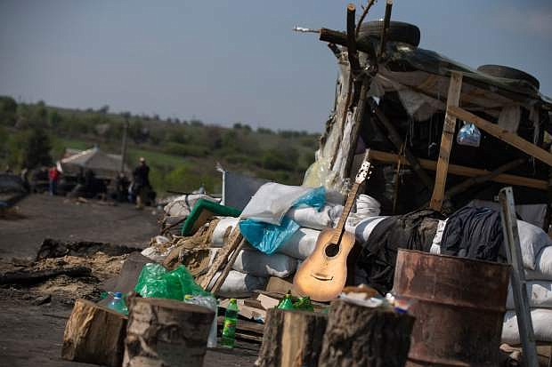 A guitar lies abandoned at a pro-Russian insurgent checkpoint that has been used to block access to a road leading to Slovyansk, eastern Ukraine, Saturday, May 3, 2014. Local nearby residents say Ukrainian government troops opened fire on a crowd of unarmed protesters on this spot, where discarded shells and pools of blood could be seen. (AP Photo/Alexander Zemlianichenko)