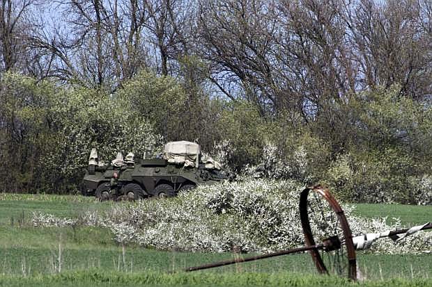 Russian solder patrols near army vehicle in a field about 2 kilometers (1,24 miles) from the Ukrainian border at Novoshakhtinsk, Rostov region, Russia, Monday, April 28, 2014. (AP Photo/Pavel Golovkin)