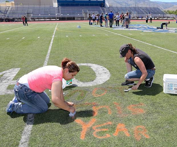 Carson High School parents Janet DeLao, left, and Liduvina Velazquez remove graffitti that was spray painted onto the football field.