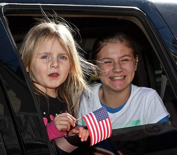 4-year-old Colbie Gragg waves an American flag Wednesday while she and her friend Danielle Vandusen, 11, ride in an SUV pulling a float in the parade.