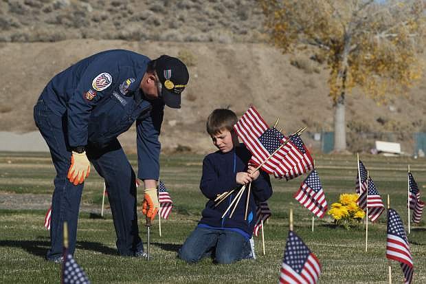 Navy veteran Johnie McDowell and Boy Scout Kaysie Beauford, 11, work as a team planting flags at the headstones of military veterans at Lone Mountain Cemetery on Tuesday morning. Nearly 1,300 flags were placed at veteran headstones by a small group of volunteers.