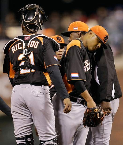 The Netherlands&#039; Diegomar Markwell, second from right, walks off the mound after being relieved by manager Hensley Meulens, right, during the fifth inning of a semifinal game of the World Baseball Classic against the Dominican Republic in San Francisco, Monday, March 18, 2013. Also pictured at left is Dashenko Ricardo. (AP Photo/Ben Margot)