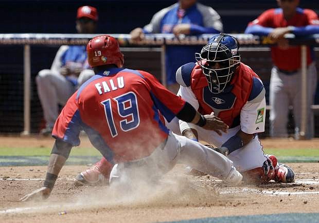 Puerto Rico&#039;s Irvin Falu (19) is tagged out at home plate by Dominican Republic catcher Carlos Santana during the third inning of a World Baseball Classic game in Miami, Saturday, March 16, 2013. (AP Photo/Alan Diaz)