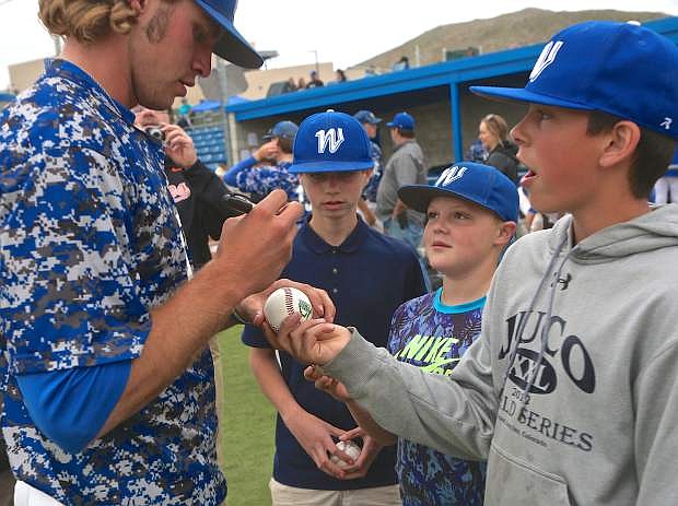 Wildcats center fielder D.J. Peters signs baseballs for young fans a week ago Friday following WNC&#039;s final home game against College of Southern Nevada at John L. Harvey Field.