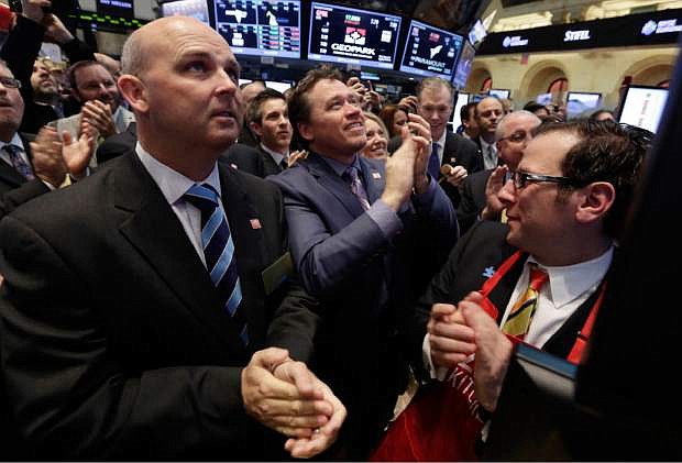 Zoes Kitchen President and CEO Kevin Miles, center, and company CFO Jason Morgan, left, applaud as their IPO begins trading, on the floor of the New York Stock Exchange, Friday, April 11, 2014. Weaker earnings at JPMorgan Chase are dragging bank stocks lower in early trading.Technology and biotech stocks also fell, a day after the worst rout for the Nasdaq composite index since 2011.(AP Photo/Richard Drew)