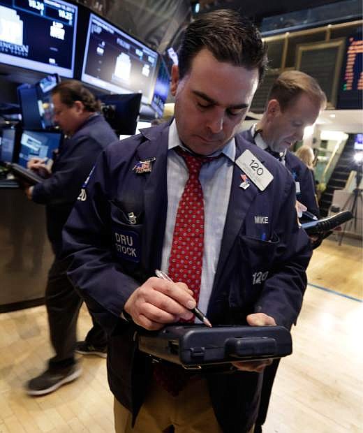 Trader Michael Iozzi, center, works on the floor of the New York Stock Exchange Monday, Dec. 16, 2013. U.S. stocks rose sharply on Monday, powered by two big corporate deals and news that suggests the economy is getting stronger.  (AP Photo/Richard Drew)