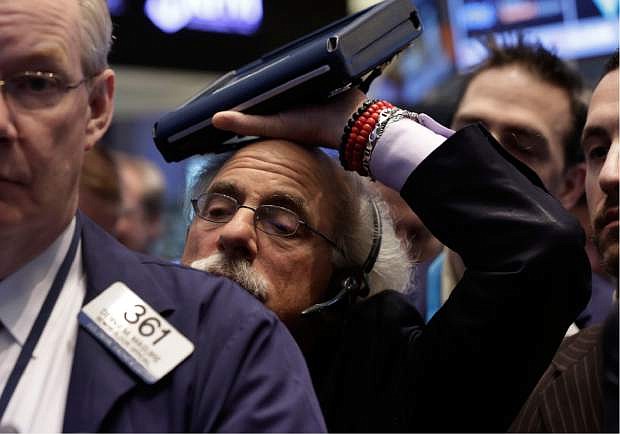Trader Peter Tuchman rests his handheld device on his head as he works on the floor of the New York Stock Exchange Friday, Jan. 31, 2014. Stocks fell sharply in early trading Friday, as investors fretted over disappointing earnings from companies like Amazon.com and more trouble in overseas markets. (AP Photo/Richard Drew)