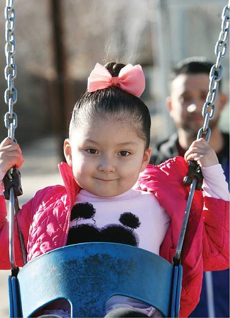 Valerie Ayala, 4, smiles while swinging in the warm sunshine on Monday afternoon at Mills Park.
