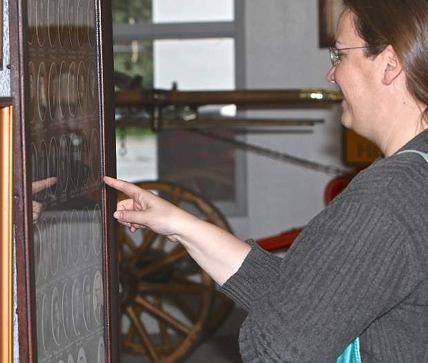 Jenny Vlcan of Carson City points to an old photo containing both her great and great-great grandfather&#039;s at the fire department museum Saturday.