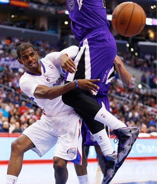 Los Angeles Clippers guard Chris Paul passes the ball around Sacramento Kings center DeMarcus Cousins during the first half of an NBA basketball game in Los Angeles, Sunday, April 12, 2014. (AP Photo/Danny Moloshok)
