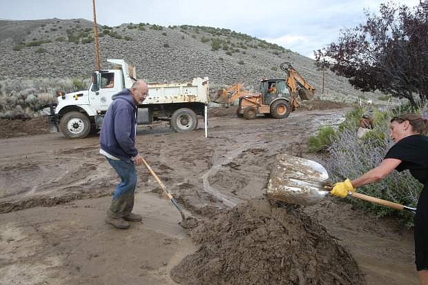 Carson River Road resident Jerry Vivant clears mud and debris from his driveway after a culvert overflowed and more than 3-feet of mud washed across the road on Monday afternoon.