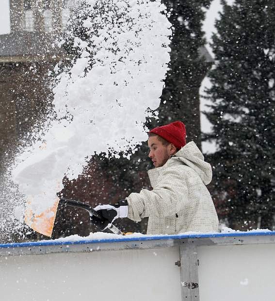 Caleb Price shovels snow off the ice at the Arlington Square Ice Rink on Tuesday afternoon.