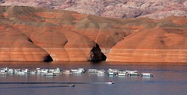 FILE - Houseboats are moored on Lake Powell in Bullfrog, Utah, in this July 12, 2006 file photo. The lake&#039;s former, higher levels are marked by the bathtub-like rings on the embankment, rear.  After back-to-back driest years in a century on the Colorado River, federal water managers are announcing a historic step to slow the flow of water from a massive reservoir upstream of the Grand Canyon to the huge Lake Mead reservoir behind Hoover Dam near Las Vegas. The U.S. Bureau of Reclamation is announcing Friday, Aug. 16, 2013, that the move to keep more water in Lake Powell will lower the water level of Lake Mead by about 20 feet in 2014. (AP Photo/Douglas C. Pizac, File)