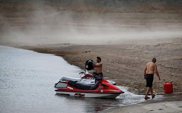 People prepare to launch watercraft as wind kicks up dust on an area that was once underwater at the Boulder Harbor boat ramp in the Lake Mead National Recreation Area, Monday, May 18, 2015, near Boulder City, Nev. Federal water managers are projecting Lake Mead will drop to levels in January 2017 that could force supply cuts to Arizona and Nevada. (AP Photo/John Locher)