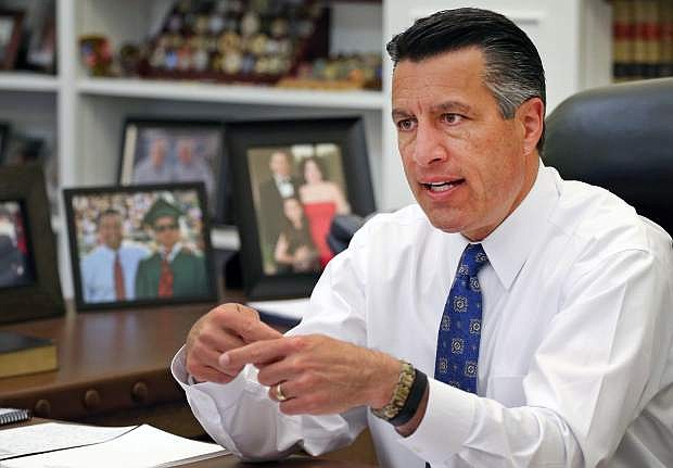 FILE - In this April 17, 2015, file photo, Nevada Gov. Brian Sandoval sits in his office at the Capitol in Carson City. Sandoval says he&#039;s considering legal action to force the U.S. Bureau of Land Management to pony up some money to pay for roundups of wild horses that have been put on hold because of budgetary constraints. Sandoval said Tuesday, April 26, 2016, if the Interior Department refuses to provide the necessary funding, he&#039;ll &quot;pursue all legal options&#039;&#039; to protect Nevada&#039;s ranchers and rural communities. (AP Photo/Cathleen Allison, File)