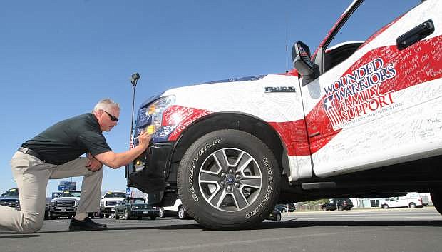 Capital Ford General Manager Tim Milligan signs one of two Ford vehicles traveling in the sixth annual Wounded Warriors High Five Tour on Tuesday. The event visits American cities to thank military families for their sacrifices.