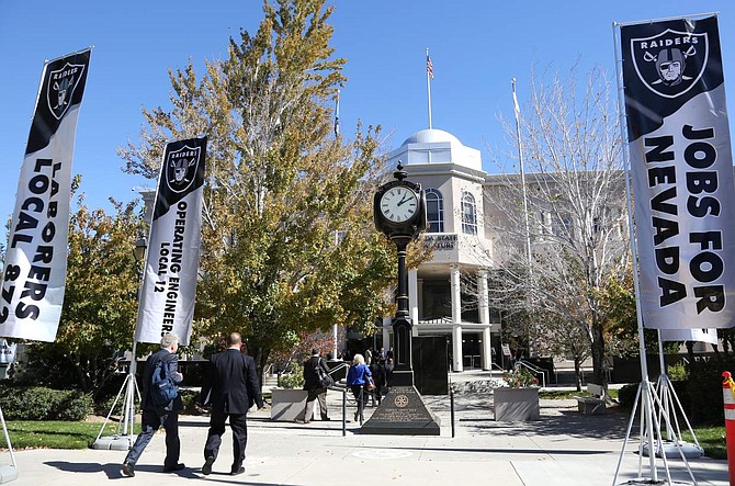 Lobbyist walk past banners outside the Legislature Building supporting the building of a football stadium in Las Vegas.