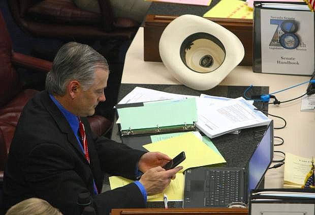 Senator James Settelmeyer checks his phone during a recess on Monday.
