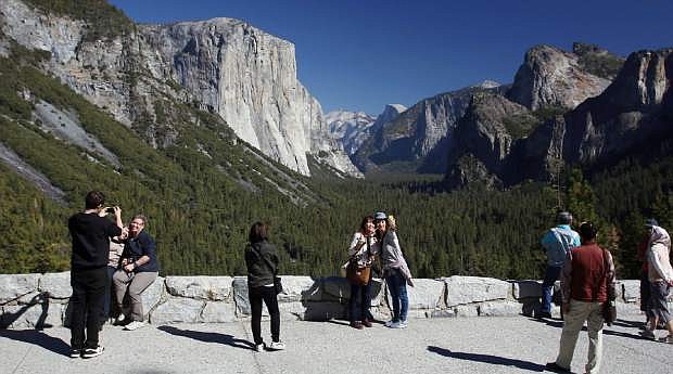 File - In this Oct. 17, 2013 file photo, visitors at Tunnel View, like Kaori Nishimura and Eriko Kuboi, from Japan, center facing, enjoy the views of Yosemite National Park, Calif. Tunnel View is a scenic vista which shows off El Capitan, Half Dome and Bridalveil Fall. Yosemite National Park is celebrating the 150th anniversary of President Abraham Lincoln&#039;s signing of the Yosemite Grant Act, Monday June 30, 2014, which protected Yosemite Valley and Mariposa Grove. (AP Photo/Gary Kazanjian, File)