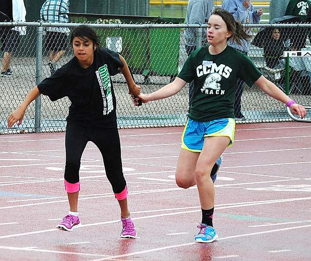 Churchill County Middle School runners Leslie Duenas, left, takes the baton from Stephanie Celine during the 4x200-meter relay on Wednesday at the Edward Arciniega Complex.