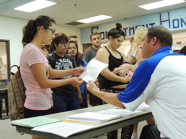Linda Arreola, a sophomore at Carson High School, receives her schedule from Gavin Ward,  school vice principal, Tuesday, as classmates await their turns. Among courses listed for Arreola were algebra, psychology, history and musicianship in strings and wind ensemble. Her instruments are violin and trumpet. The first day of school at Carson High is Monday. Look for the Appeal&#039;s Back to School Section in today&#039;s edition.