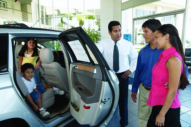 Salesman shows a car to family in the  showroom.