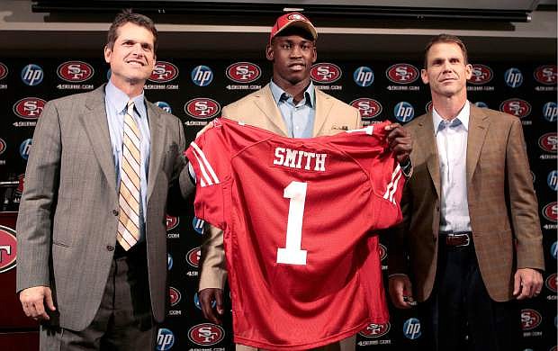 FILE - In this April 29, 2011, file photo, Aldon Smith, center, the first-round draft pick of the San Francisco 49ers, holds up a jersey next to coach Jim Harbaugh, left, and general manager Trent Baalke at a news conference at the NFL football team&#039;s training facility in Santa Clara, Calif. Baalke is committed to supporting linebacker Smith like a family member in the wake of his latest legal trouble--and keeping Smith around for the long haul, too. (AP Photo/Jeff Chiu, File)